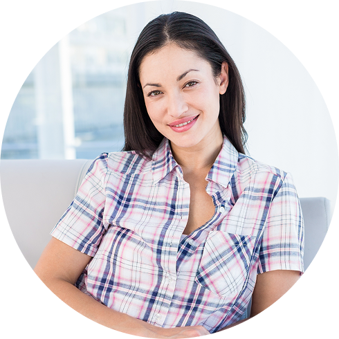 Smiling woman in plaid shirt sitting on a couch in bright room