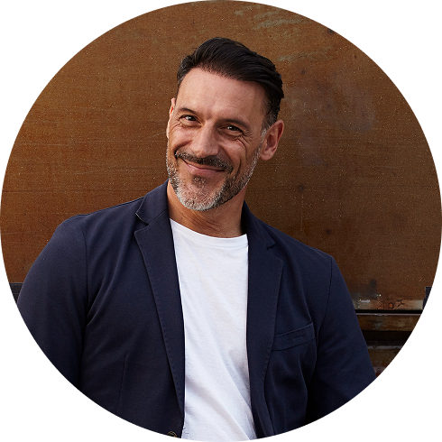 Smiling man with salt-and-pepper beard wearing blazer and white shirt