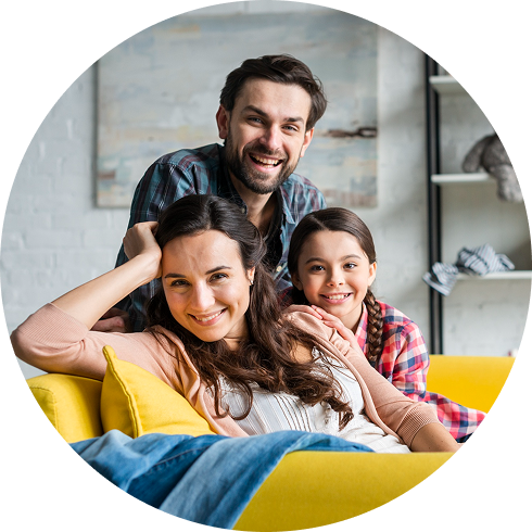 Smiling family relaxing together on a yellow couch at home