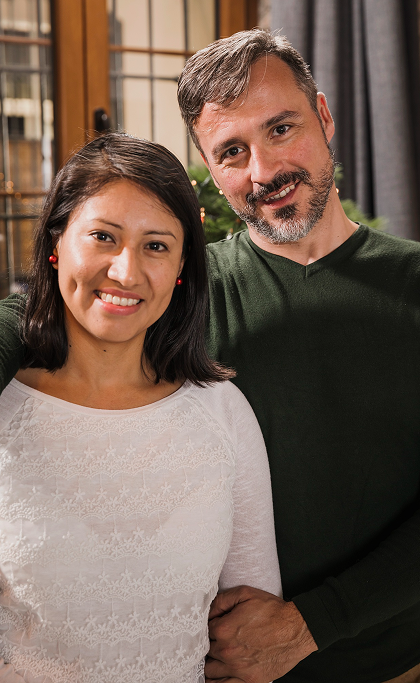 Smiling couple standing close together indoors with warm lighting