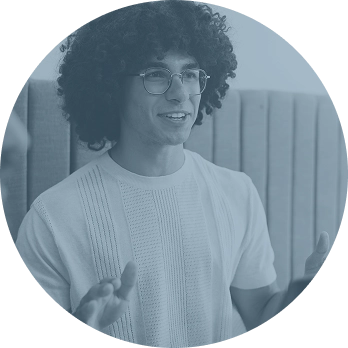Man with curly hair and glasses talking while gesturing with hands