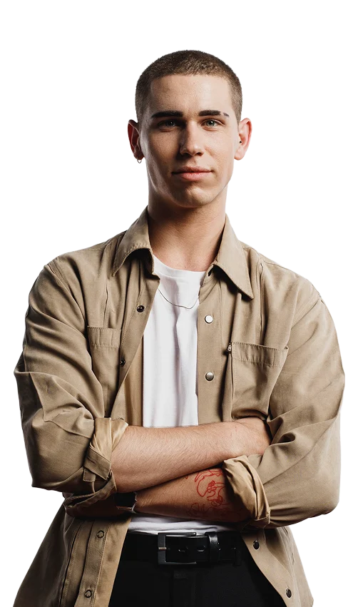 Confident young man with short hair standing with arms crossed, wearing a beige shirt over a white t-shirt